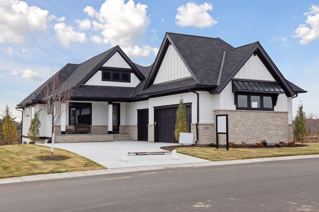 modern inspired farmhouse featuring a garage, driveway, a front lawn, and stone siding