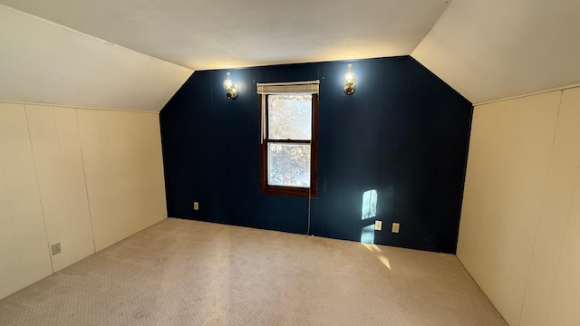 additional living space featuring vaulted ceiling and light colored carpet