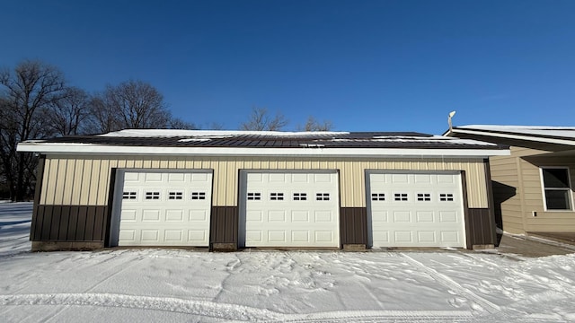 snow covered garage featuring a detached garage