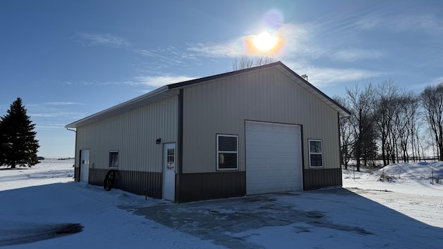 view of snow covered exterior with a garage and an outbuilding