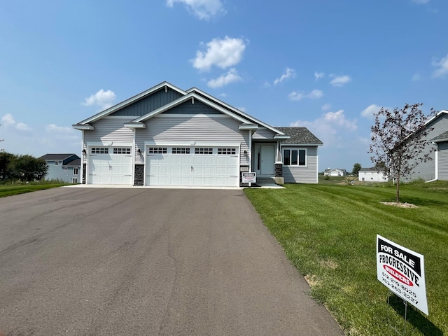 view of front of house with a garage, stone siding, aphalt driveway, and a front lawn