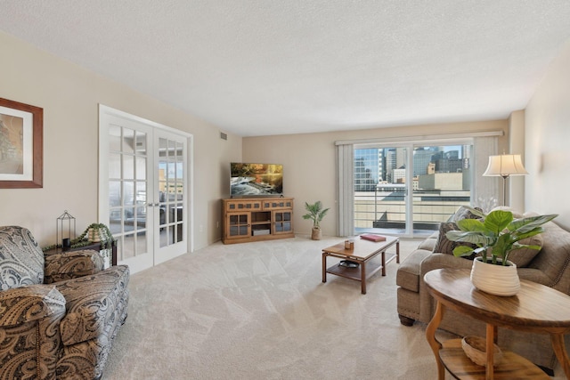 living area with light carpet, visible vents, a textured ceiling, and french doors