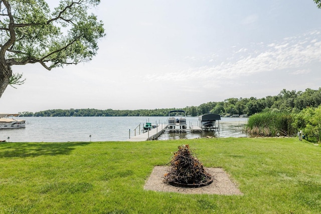 view of dock featuring a water view, a lawn, and a fire pit