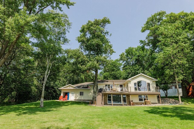 rear view of house featuring stone siding, a wooden deck, stairs, and a yard