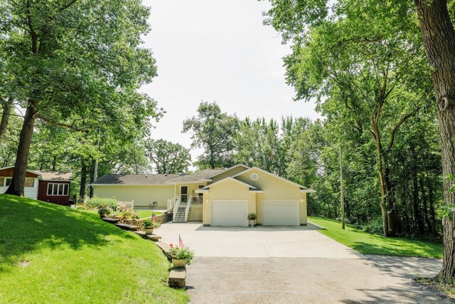 ranch-style house featuring a garage, driveway, and a front lawn