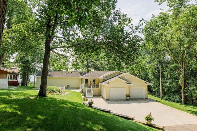 ranch-style house featuring a front yard, concrete driveway, and an attached garage