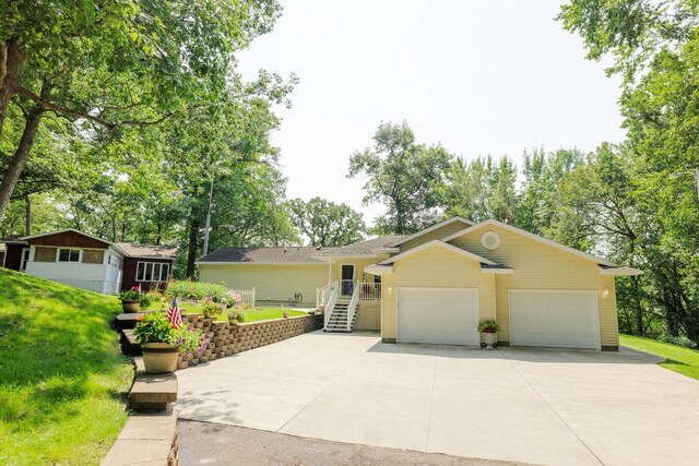 single story home featuring stairs, concrete driveway, an attached garage, and a front yard