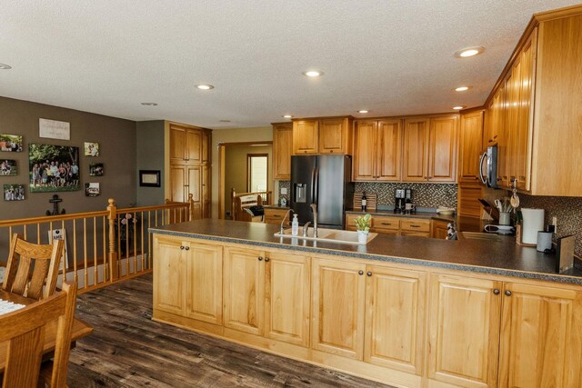 kitchen featuring stainless steel appliances, dark wood-type flooring, dark countertops, and backsplash