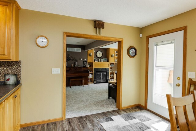 interior space featuring baseboards, a fireplace, visible vents, and wood finished floors