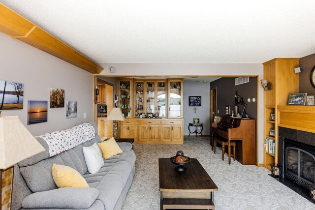 living room featuring a fireplace with flush hearth, visible vents, and light colored carpet