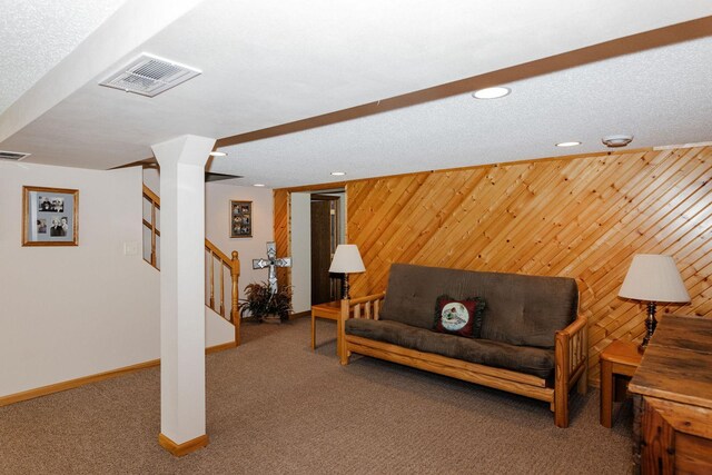 living area with carpet floors, visible vents, stairway, wooden walls, and baseboards