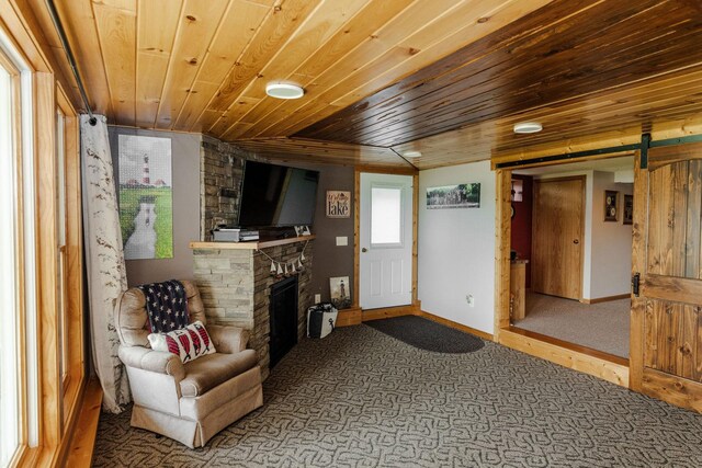 sitting room featuring a barn door, wooden ceiling, carpet floors, a fireplace, and baseboards