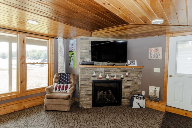 carpeted living area with wood ceiling and a stone fireplace