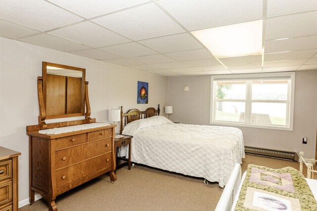 bedroom featuring a baseboard heating unit, light carpet, and a paneled ceiling