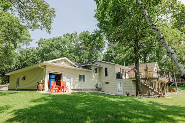 rear view of property featuring an attached garage, a yard, stairway, and a patio area