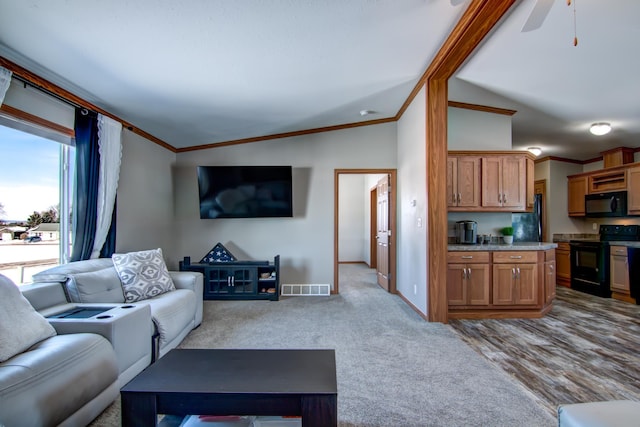 carpeted living area featuring visible vents, ornamental molding, baseboards, lofted ceiling, and ceiling fan