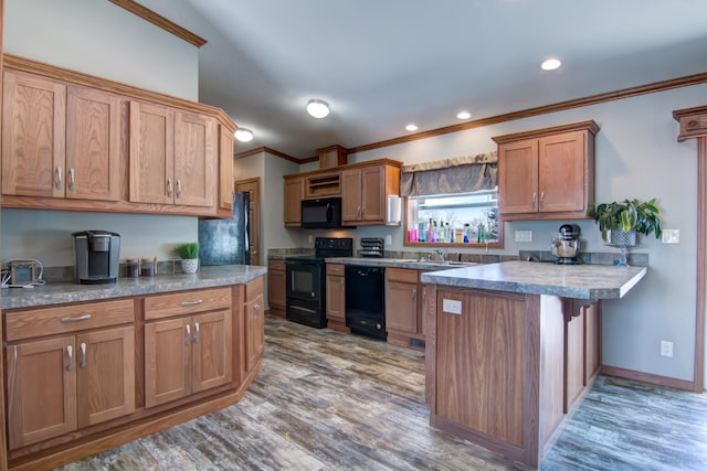 kitchen featuring black appliances, a sink, light wood-style floors, a peninsula, and crown molding