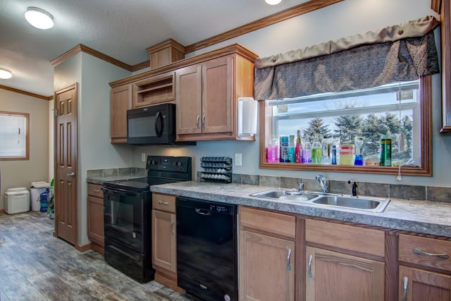 kitchen with black appliances, wood finished floors, crown molding, and a sink