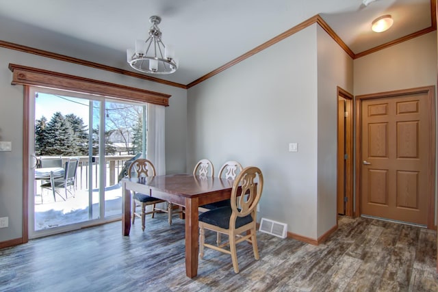 dining room with visible vents, a notable chandelier, ornamental molding, wood finished floors, and baseboards