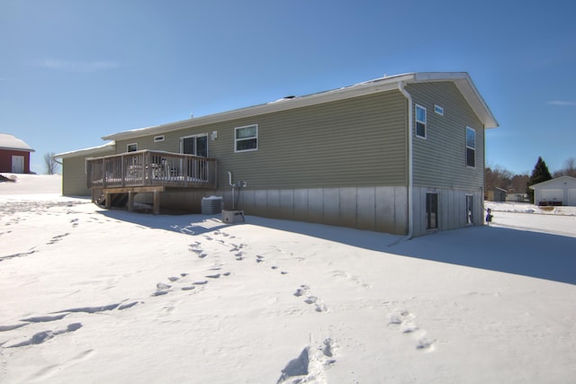 snow covered house featuring a wooden deck and central AC