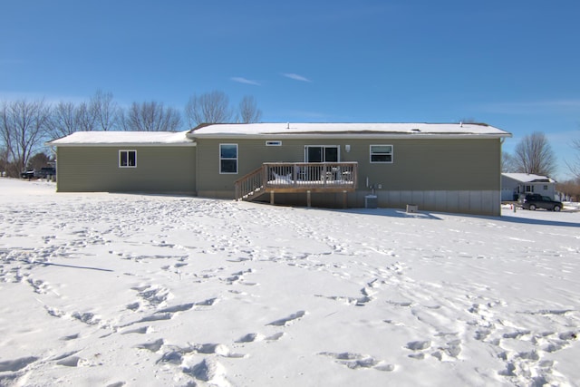 snow covered back of property with central AC unit and a deck