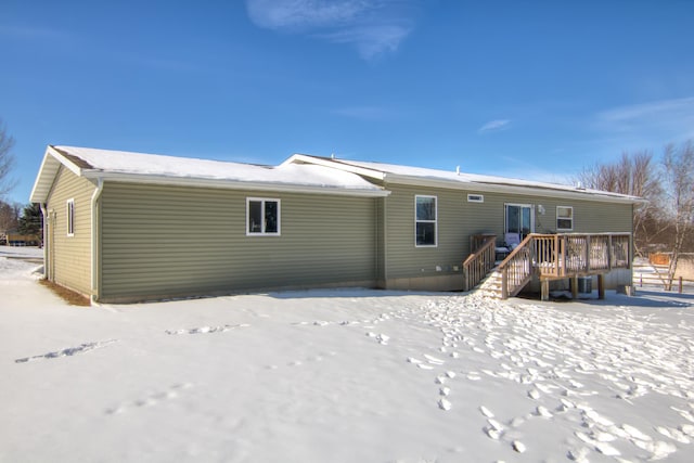 snow covered back of property with a wooden deck