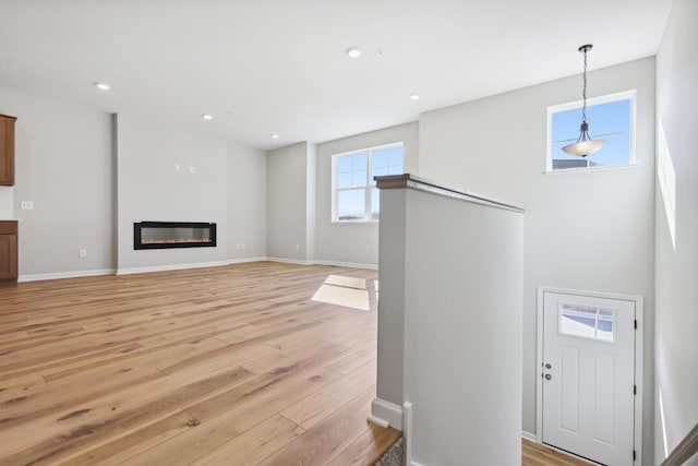 entrance foyer with light wood-style floors, a glass covered fireplace, baseboards, and recessed lighting