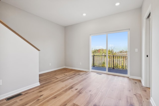 empty room with baseboards, visible vents, and light wood finished floors