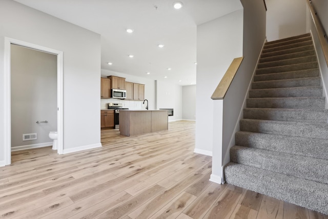 interior space featuring light wood-style flooring, recessed lighting, visible vents, baseboards, and stairway