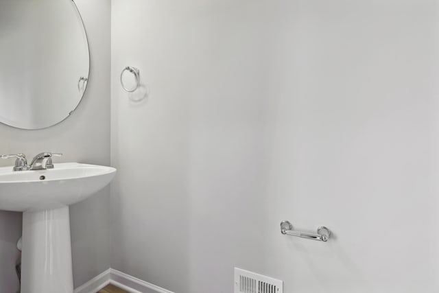 bathroom with baseboards, visible vents, and a sink