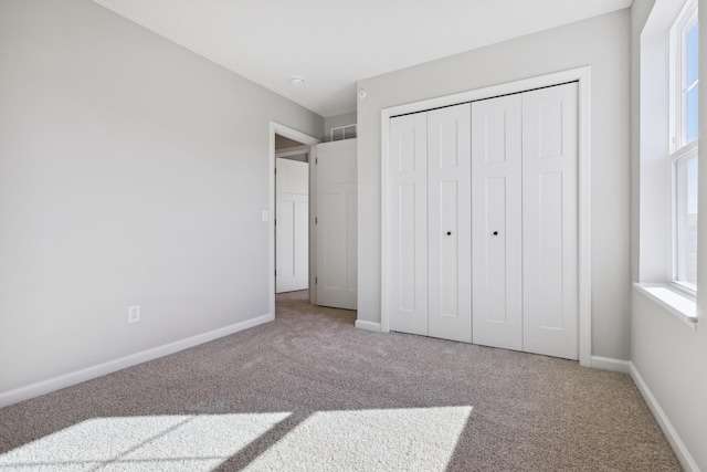 unfurnished bedroom featuring a closet, carpet flooring, visible vents, and baseboards