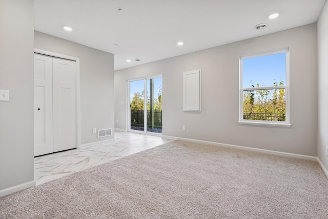 carpeted empty room with visible vents, baseboards, and recessed lighting