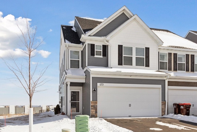 townhome / multi-family property with a garage and stone siding