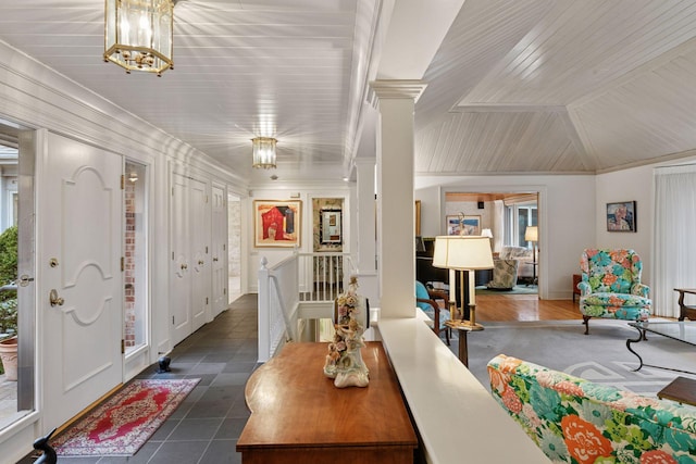 entryway featuring ornate columns, vaulted ceiling, crown molding, wooden ceiling, and dark tile patterned floors