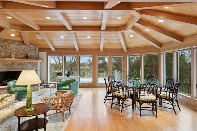 sunroom / solarium featuring lofted ceiling with beams, visible vents, wood ceiling, and a fireplace