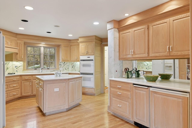 kitchen featuring light brown cabinetry, a center island, light wood-style floors, light countertops, and white double oven