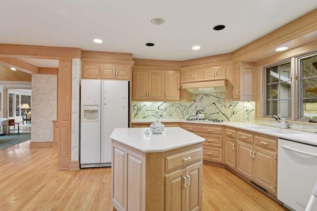 kitchen with light wood-style flooring, a sink, a center island, white appliances, and light countertops