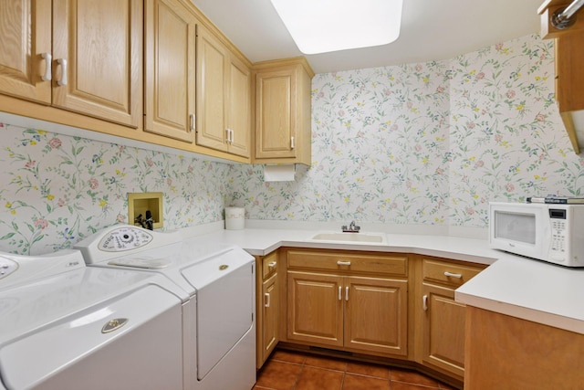 laundry area with independent washer and dryer, wallpapered walls, dark tile patterned flooring, and a sink