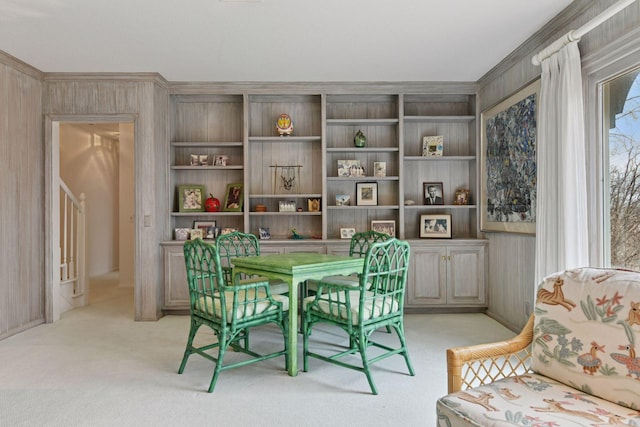 dining room with light colored carpet and wood walls