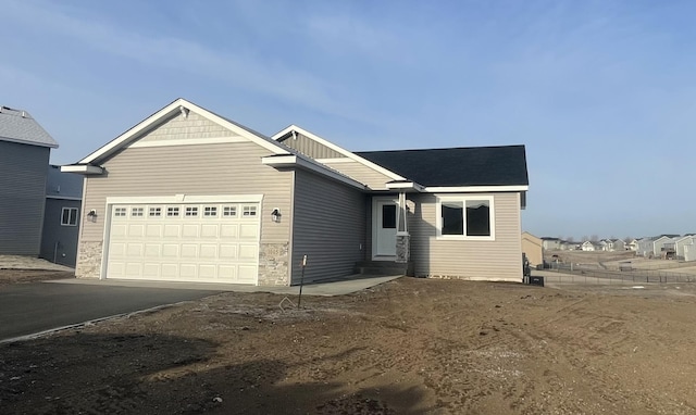 view of front of house featuring aphalt driveway, entry steps, stone siding, and a garage