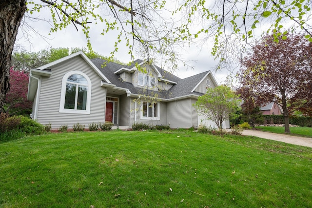 view of front facade with an attached garage, concrete driveway, a front yard, and a shingled roof