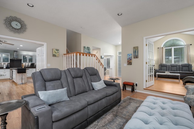 living room with light wood-type flooring, a ceiling fan, recessed lighting, baseboards, and stairs