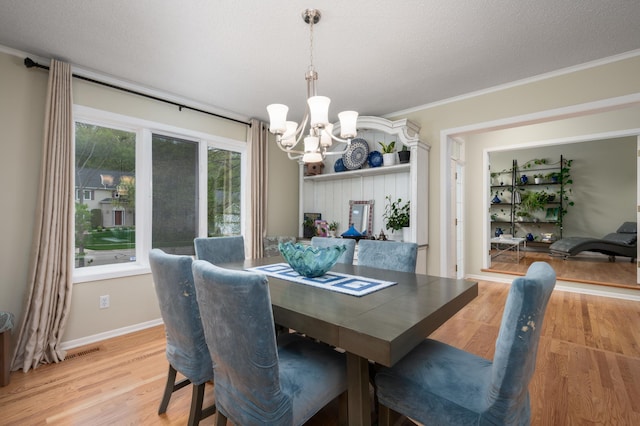 dining space with a notable chandelier, a textured ceiling, crown molding, light wood finished floors, and baseboards