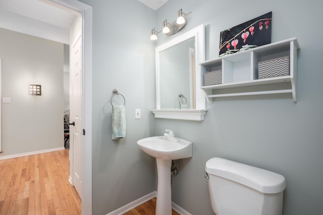 half bathroom featuring toilet, baseboards, and wood finished floors