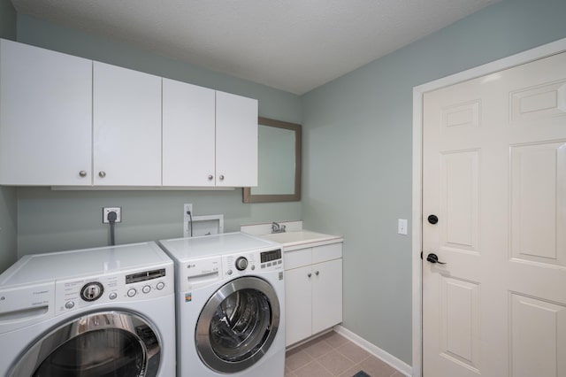 washroom with washer and clothes dryer, a sink, a textured ceiling, cabinet space, and baseboards