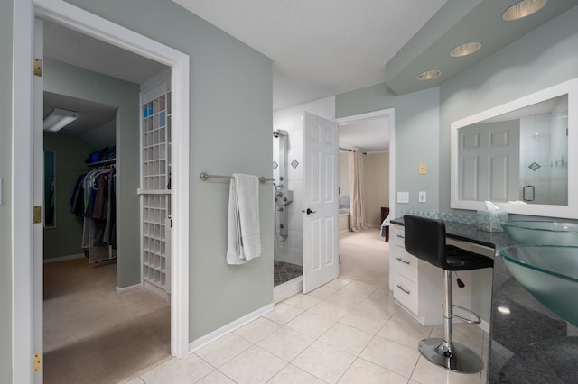 full bathroom with tile patterned flooring, a spacious closet, baseboards, and tiled shower