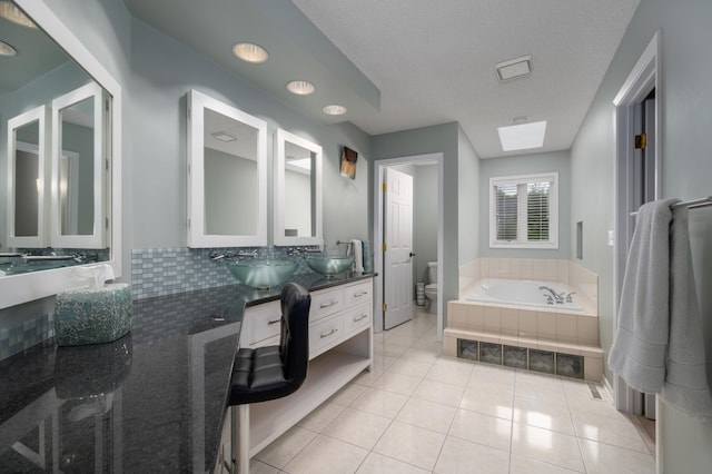 full bathroom featuring tile patterned floors, a skylight, toilet, and a sink