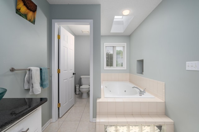 bathroom featuring vanity, a tub with jets, a skylight, tile patterned flooring, and toilet