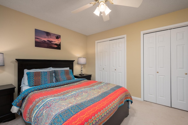 bedroom featuring baseboards, two closets, a ceiling fan, and carpet