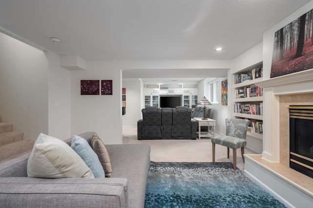 carpeted living room with recessed lighting, stairway, built in shelves, and a tiled fireplace